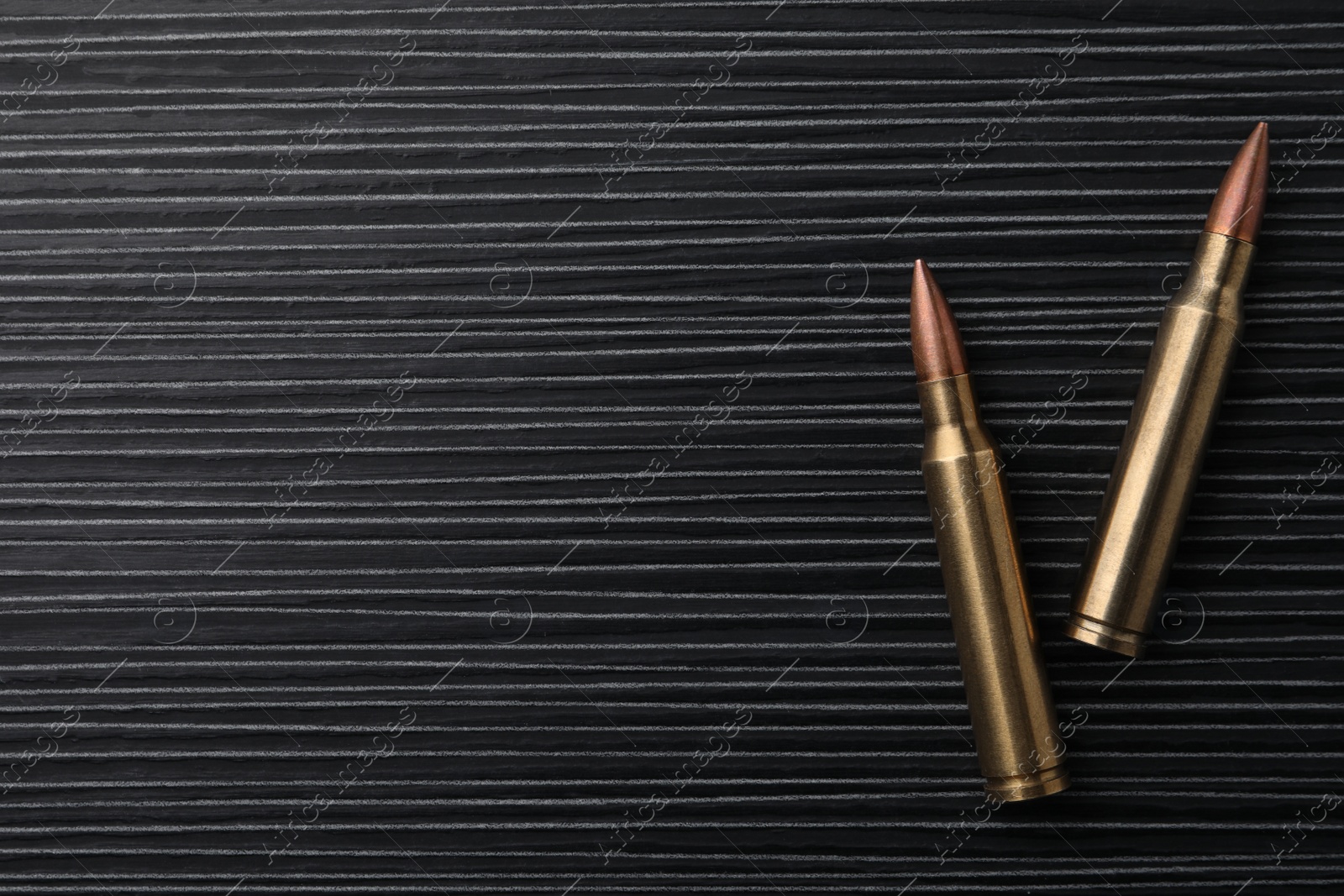 Photo of Two bullets on black wooden table, flat lay. Space for text