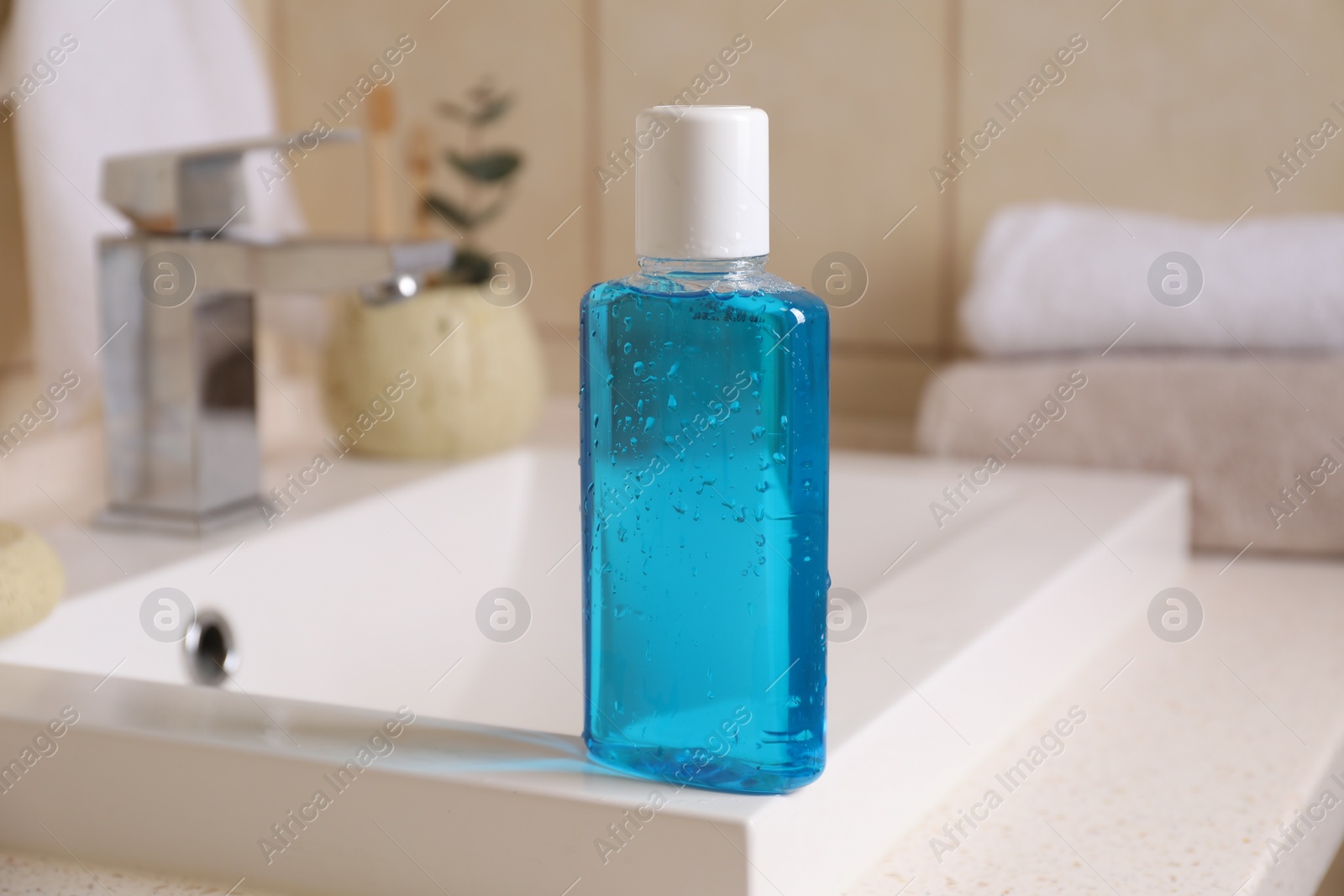 Photo of Fresh mouthwash in bottle on sink in bathroom, closeup