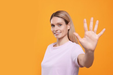 Photo of Woman giving high five on orange background, space for text