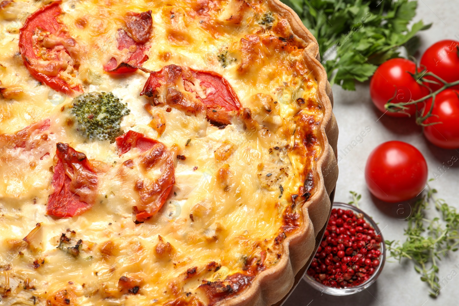 Photo of Tasty quiche with tomatoes and cheese served on light table, closeup
