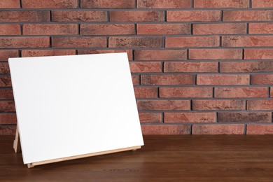 Wooden easel with blank canvas on table. Space for text