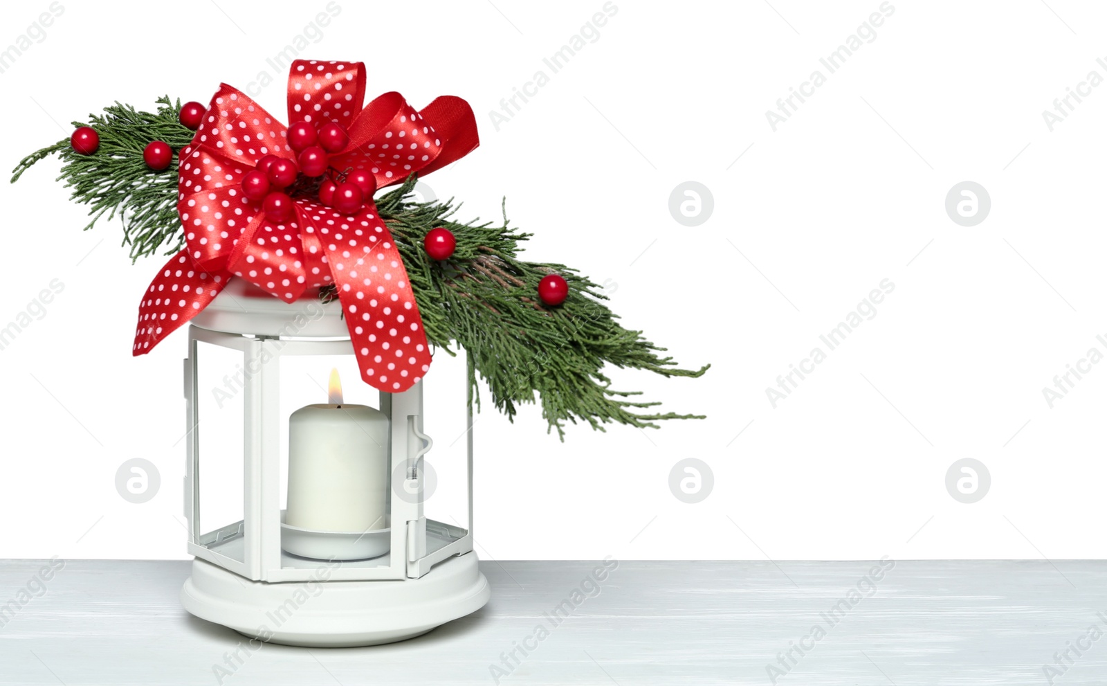 Photo of Decorated Christmas lantern with burning candle on white wooden table, space for text