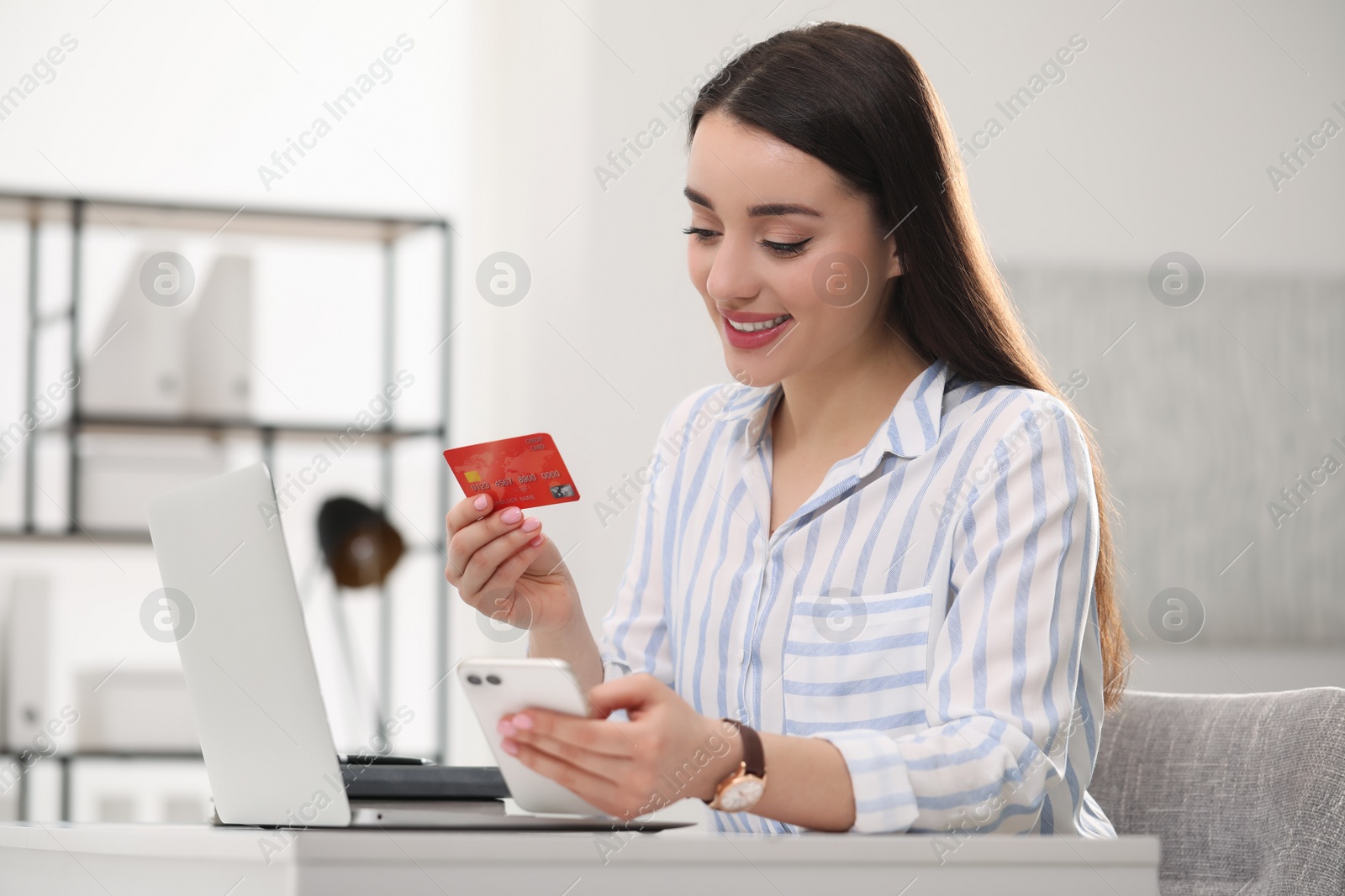 Photo of Woman with credit card using laptop and smartphone for online shopping indoors