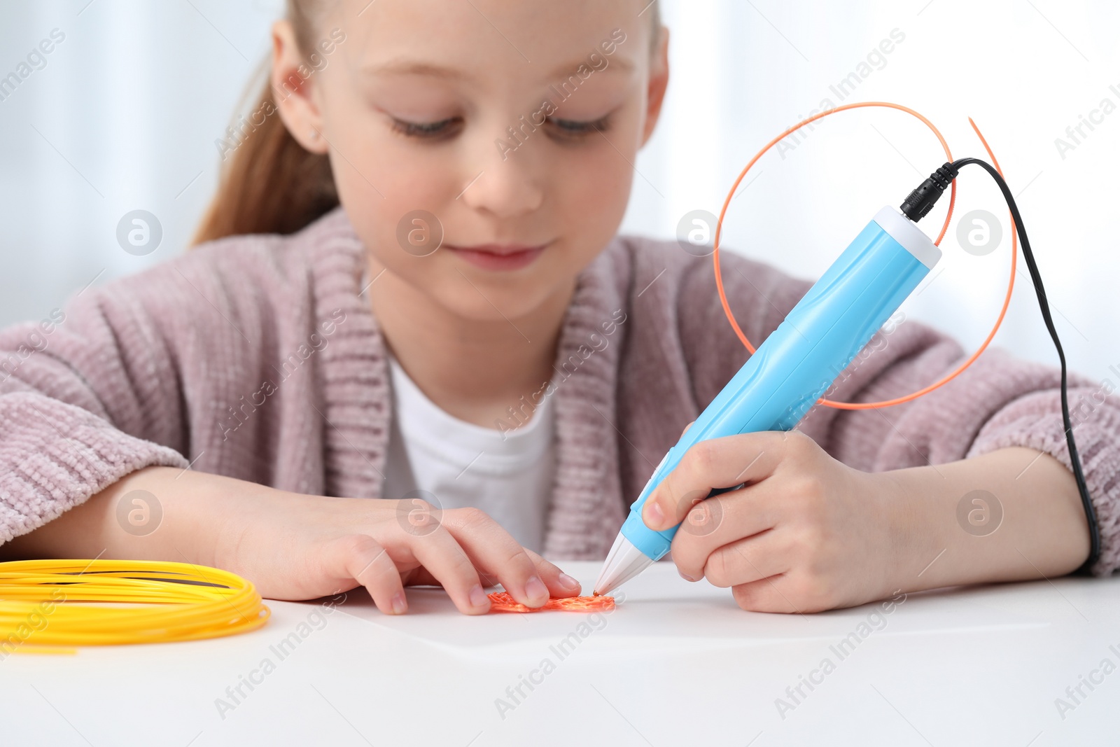 Photo of Girl drawing with stylish 3D pen at white table indoors, selective focus