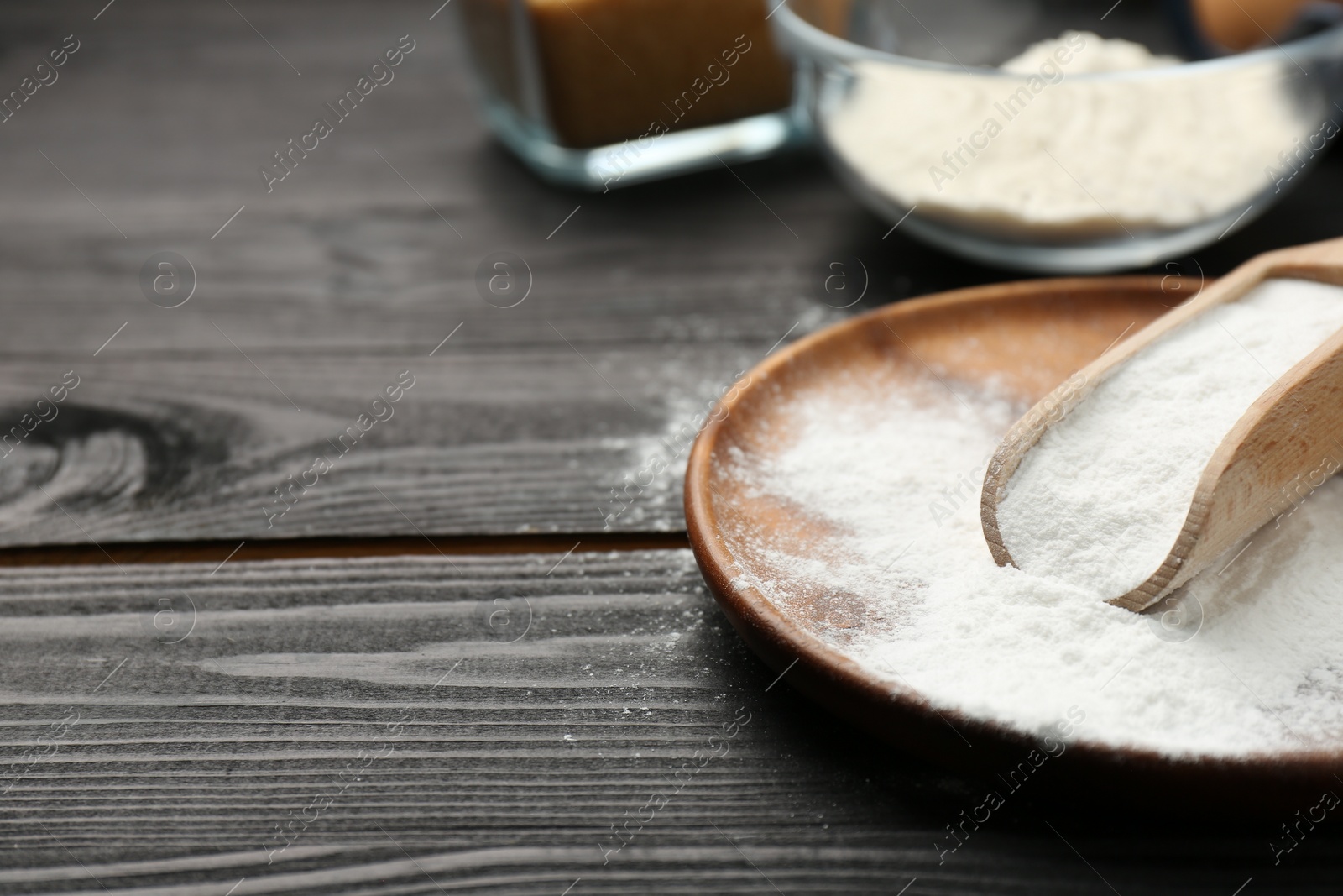 Photo of Pate and scoop with baking powder on black wooden table, closeup. Space for text