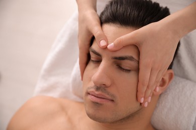 Photo of Man receiving facial massage in beauty salon, closeup