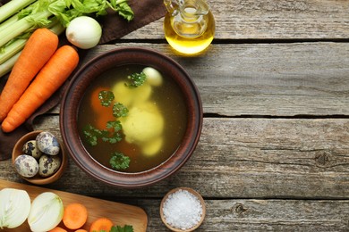 Photo of Delicious chicken bouillon and ingredients on wooden table, flat lay. Space for text