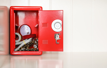 Photo of Open red steel safe with money and jewelry on shelf. Space for text