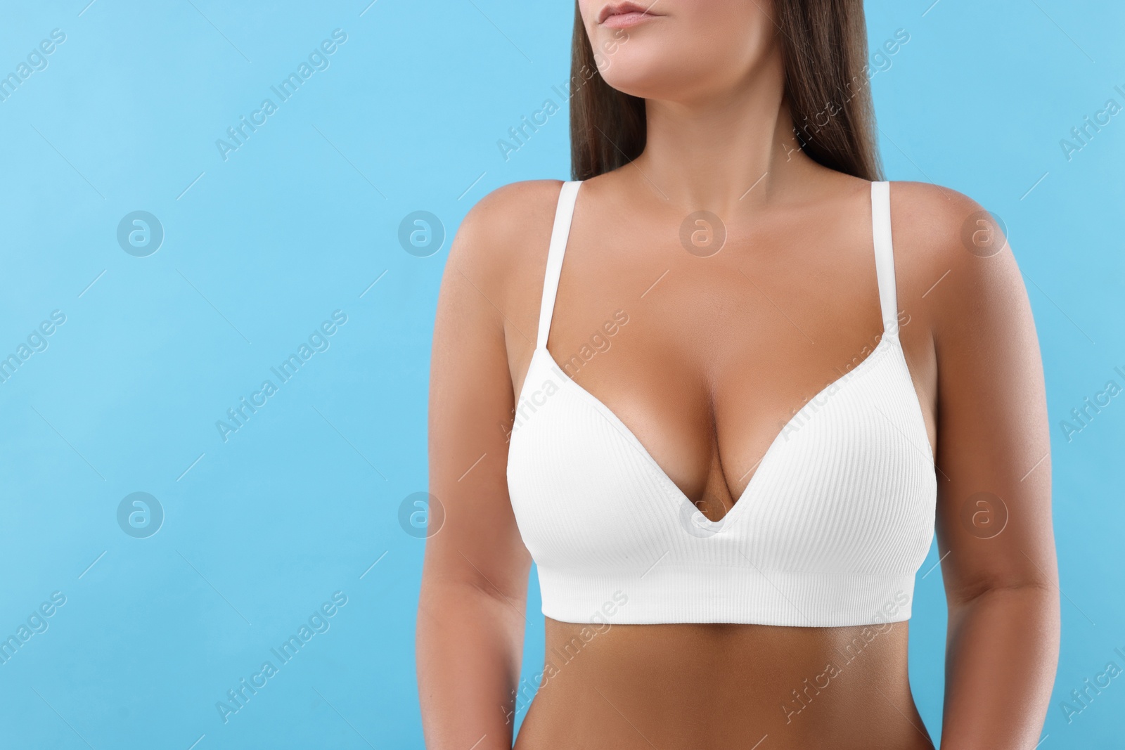 Photo of Woman with beautiful breast on light blue background, closeup. Space for text