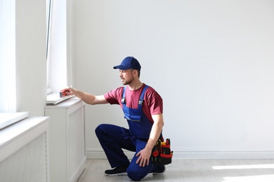 Photo of Handyman in uniform working with building level indoors. Professional construction tools