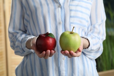 Photo of Woman holding fresh ripe red and green apples on blurred background, closeup