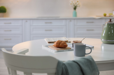 Delicious breakfast with fresh croissant and cup of hot drink in kitchen