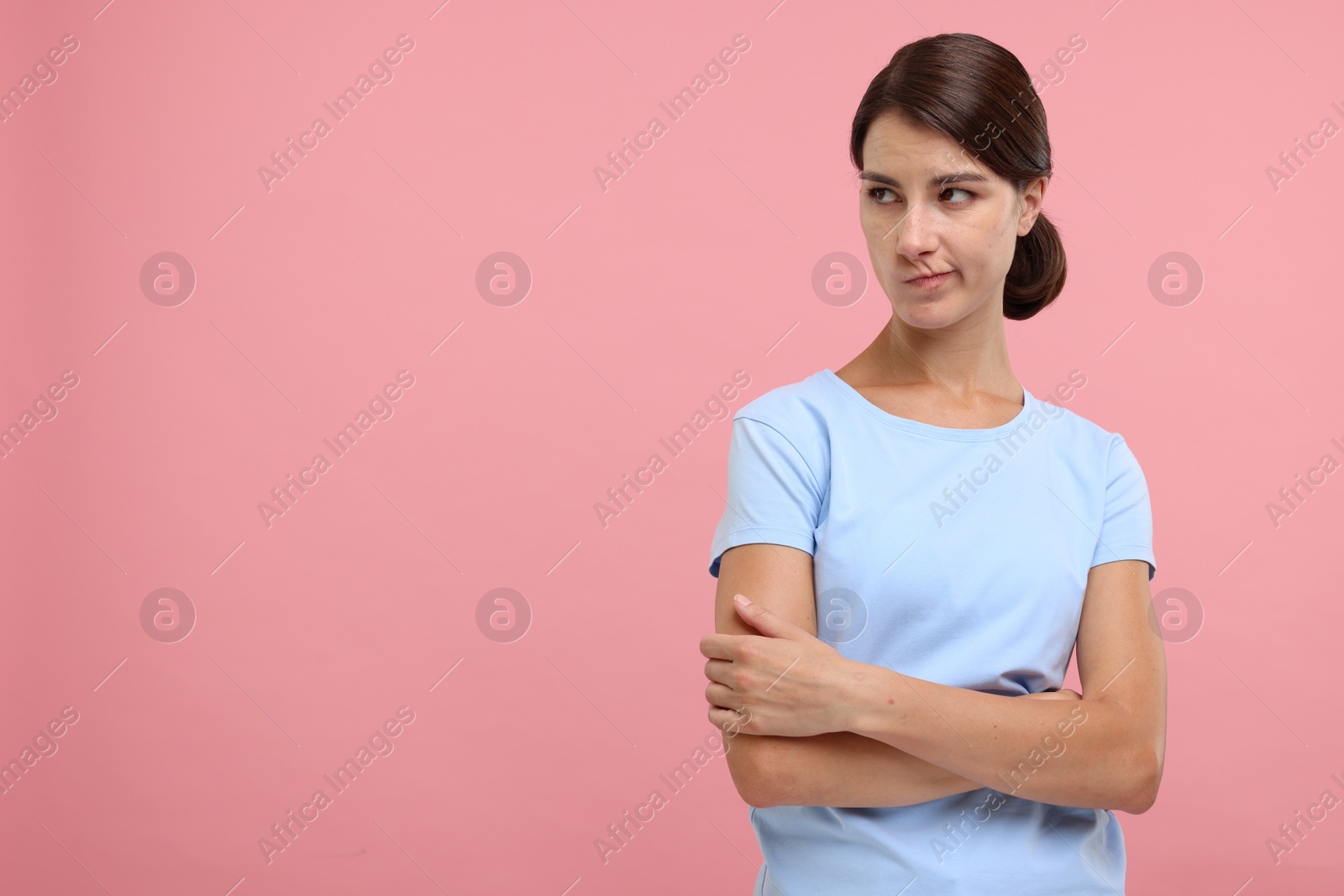 Photo of Resentful woman with crossed arms on pink background, space for text