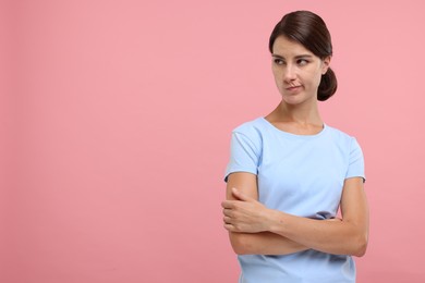 Photo of Resentful woman with crossed arms on pink background, space for text