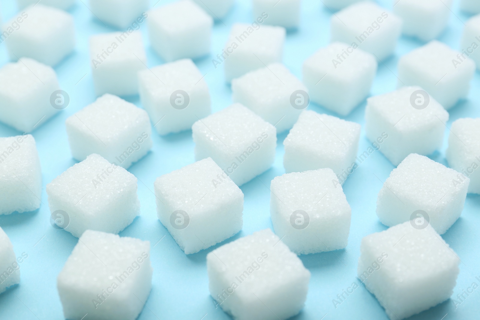 Photo of White sugar cubes on light blue background, closeup