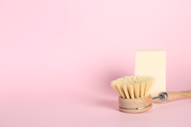 Cleaning brush and soap bar on pink background, space for text. Dish washing supplies
