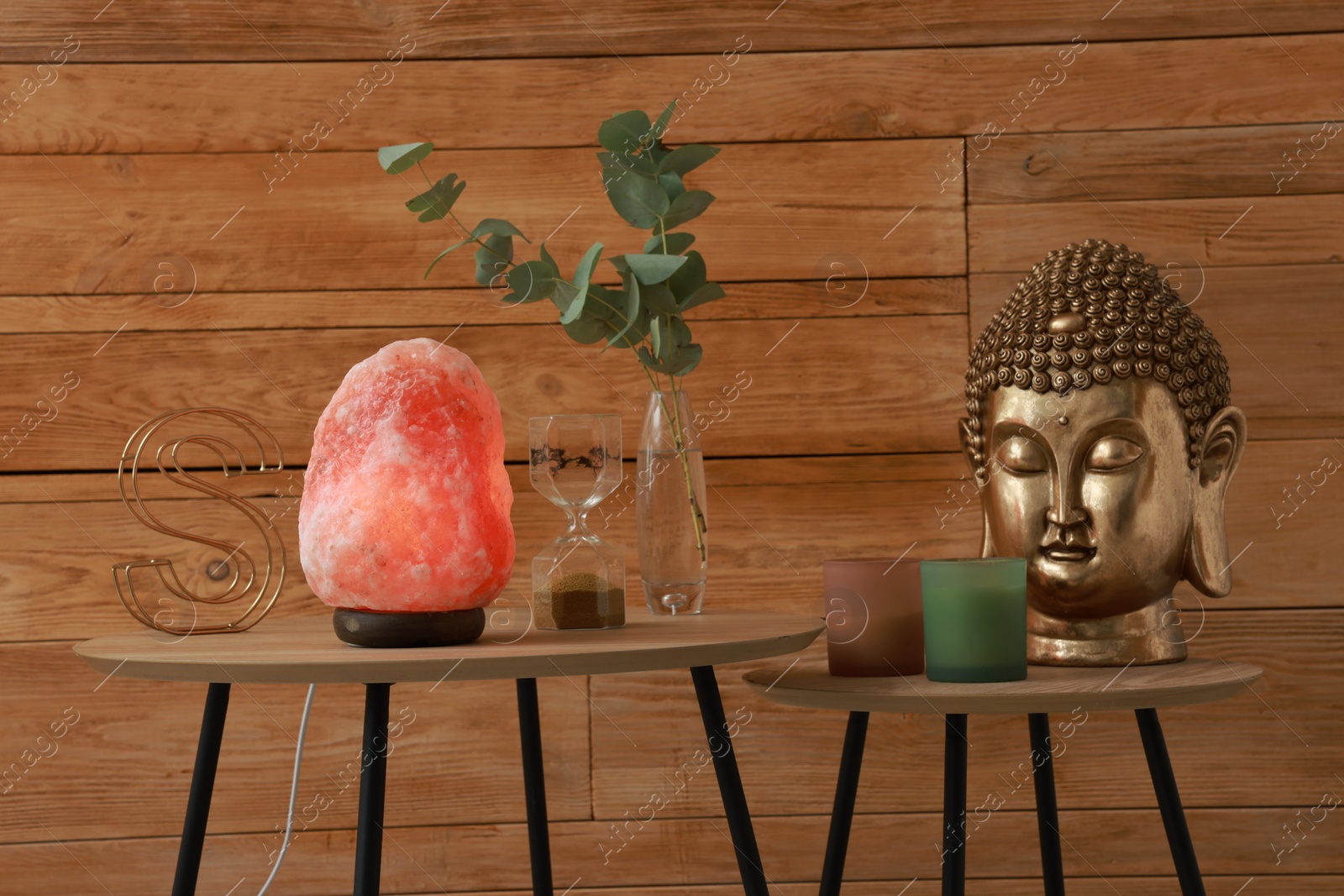 Photo of Beautiful Himalayan salt lamp, golden Buddha sculpture and decor on wooden tables indoors