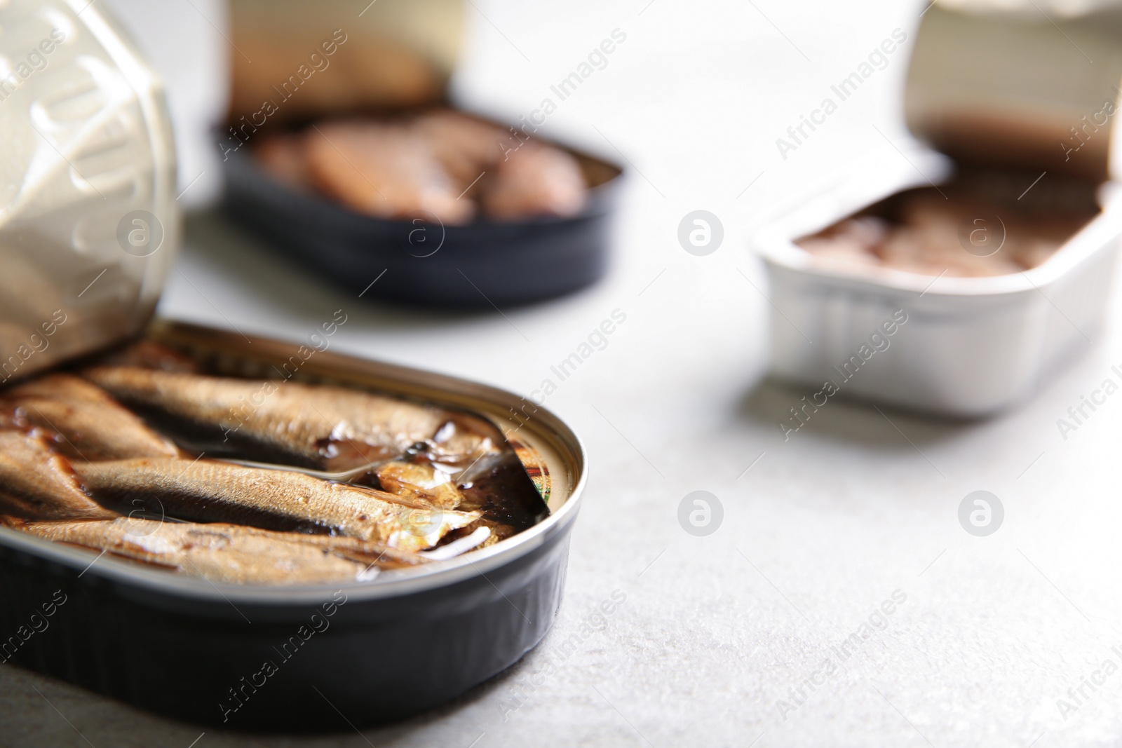 Photo of Tin can with sprats on light table, closeup. Space for text