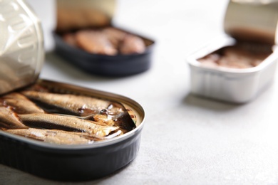 Photo of Tin can with sprats on light table, closeup. Space for text