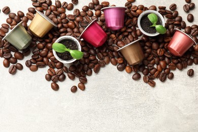 Coffee capsules with seedlings and beans on light grey table, flat lay. Space for text