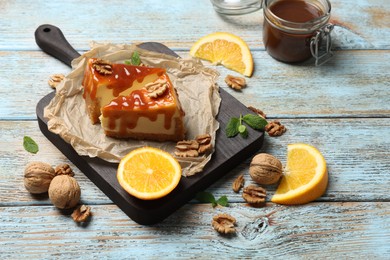 Photo of Pieces of delicious caramel cheesecake with walnuts and orange served on wooden table