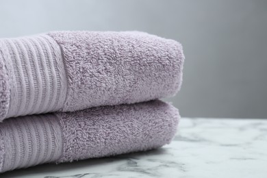 Folded violet terry towels on white marble table, closeup