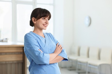 Photo of Portrait of smiling medical assistant with crossed arms in hospital. Space for text