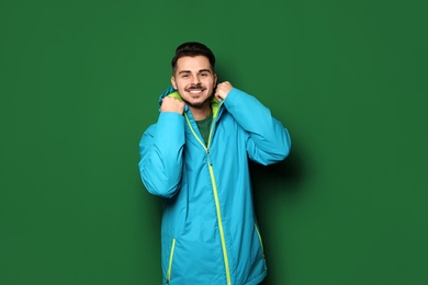 Young man wearing warm clothes on color background. Ready for winter vacation