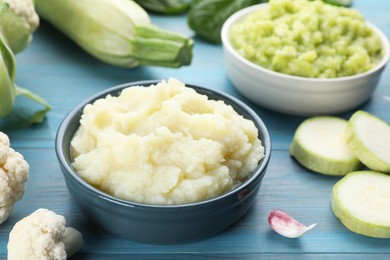 Tasty puree in bowls and ingredients on light blue wooden table, closeup