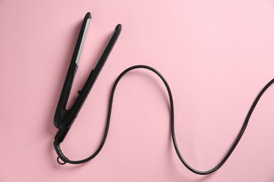 Photo of Modern flat hair iron on pink background, top view