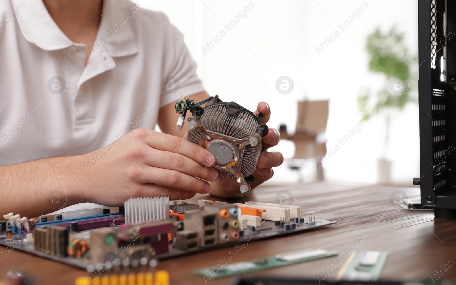 Photo of Male technician repairing computer at table indoors, closeup