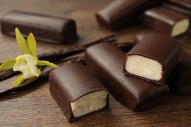 Glazed curd cheese bars, vanilla pods and flower on wooden table, closeup