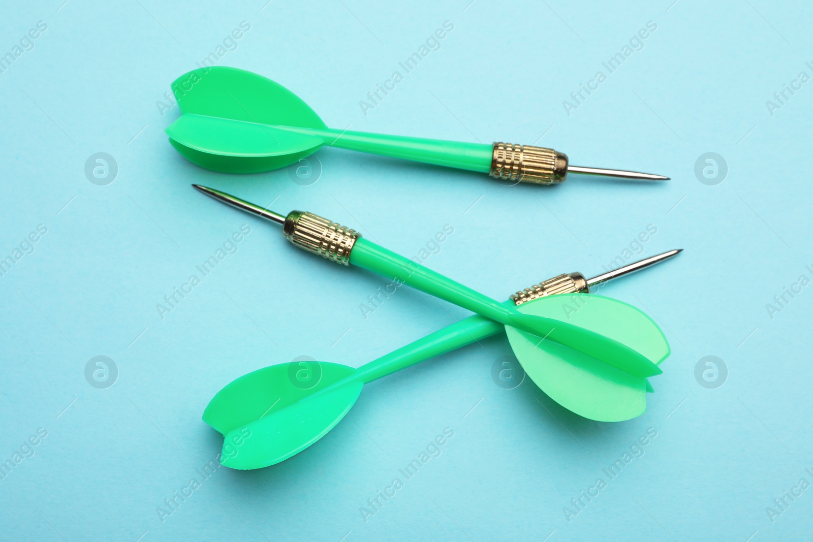 Photo of Green dart arrows on blue background, flat lay