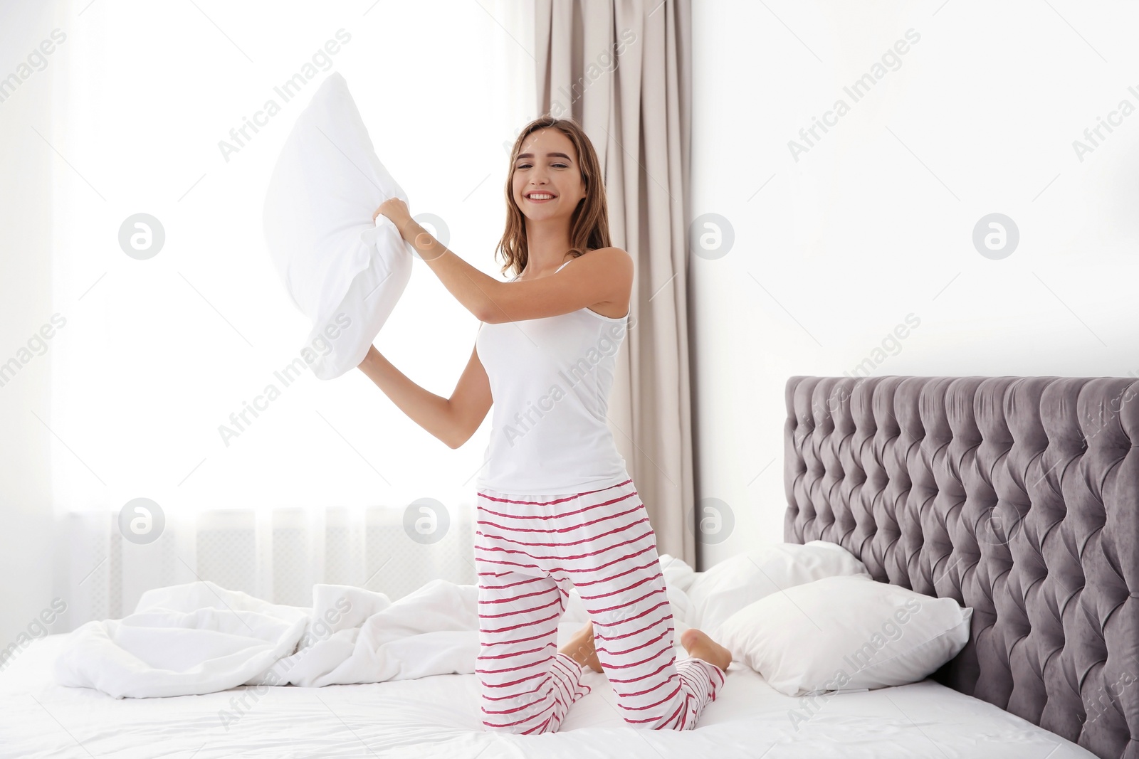 Photo of Beautiful teen girl having fun with pillow in bed at home