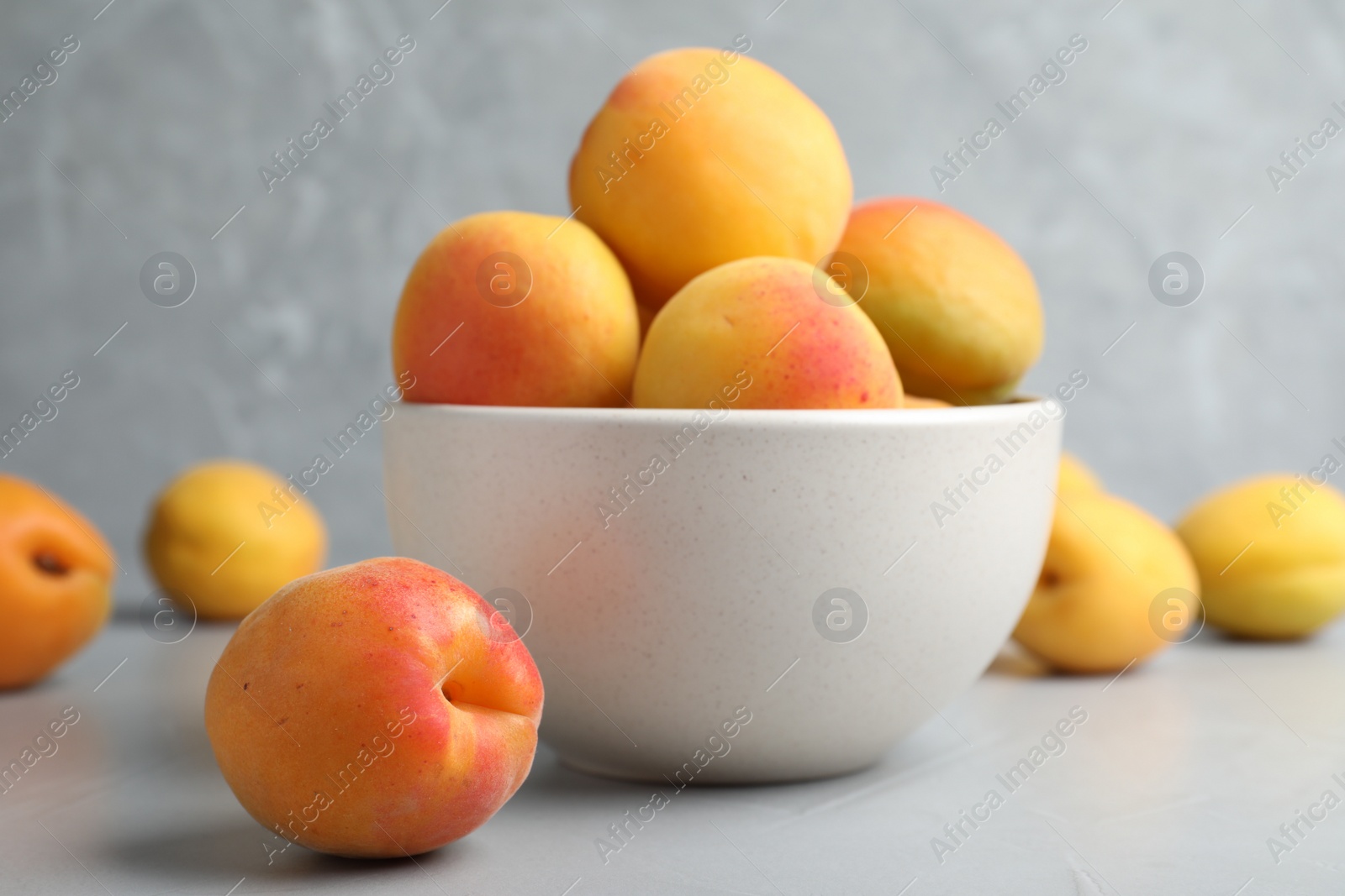 Photo of Many fresh ripe apricots on light grey table