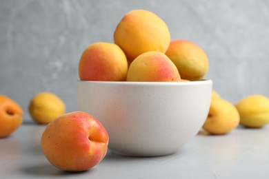 Photo of Many fresh ripe apricots on light grey table