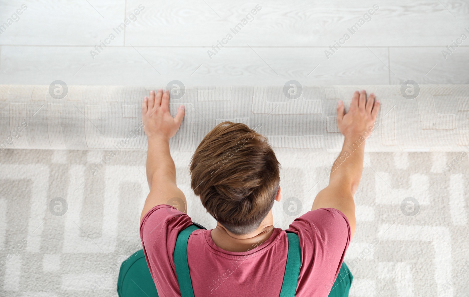 Photo of Man rolling out new carpet flooring indoors, top view