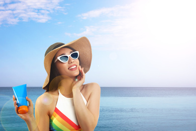 Image of Young woman with sun protection cream near sea, space for text