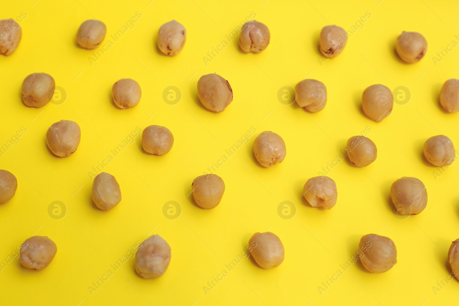 Photo of Tasty organic hazelnuts on yellow background, above view