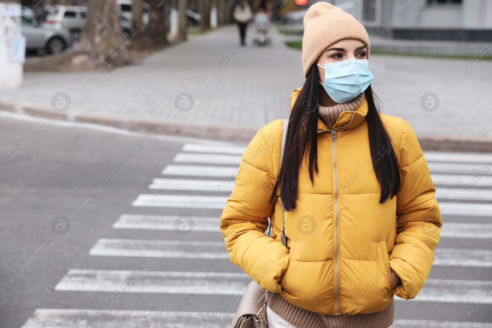 Photo of Young woman in medical face mask walking outdoors. Personal protection during COVID-19 pandemic