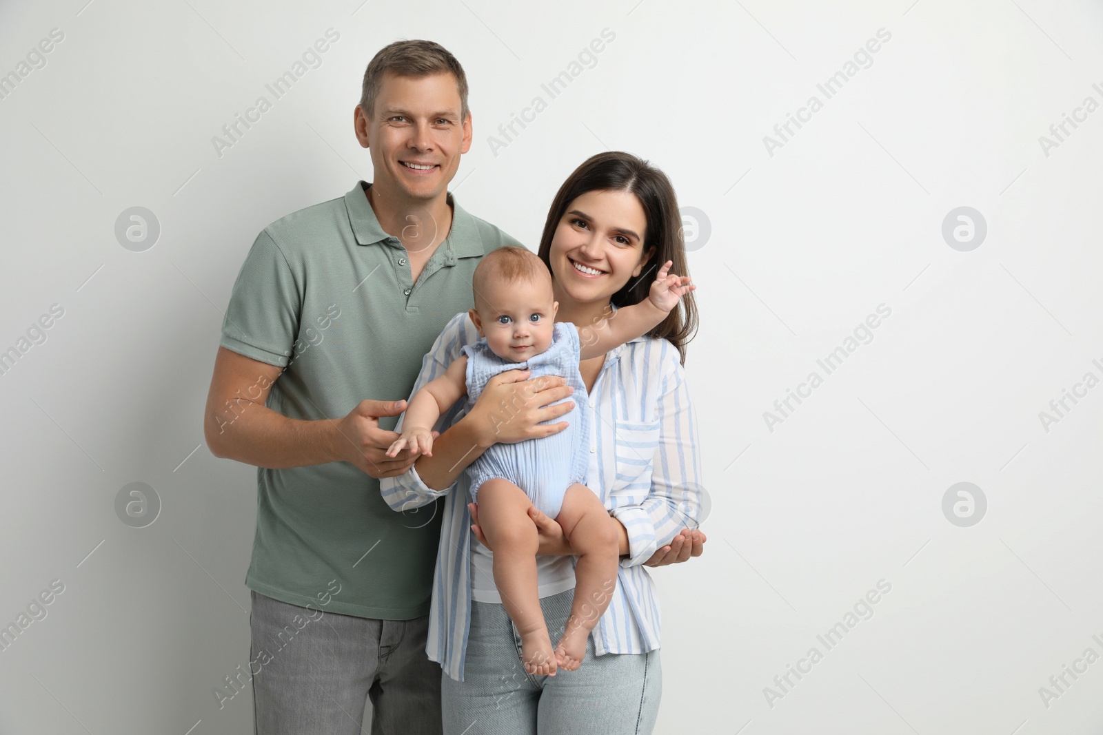 Photo of Portrait of happy family with their cute baby on white background