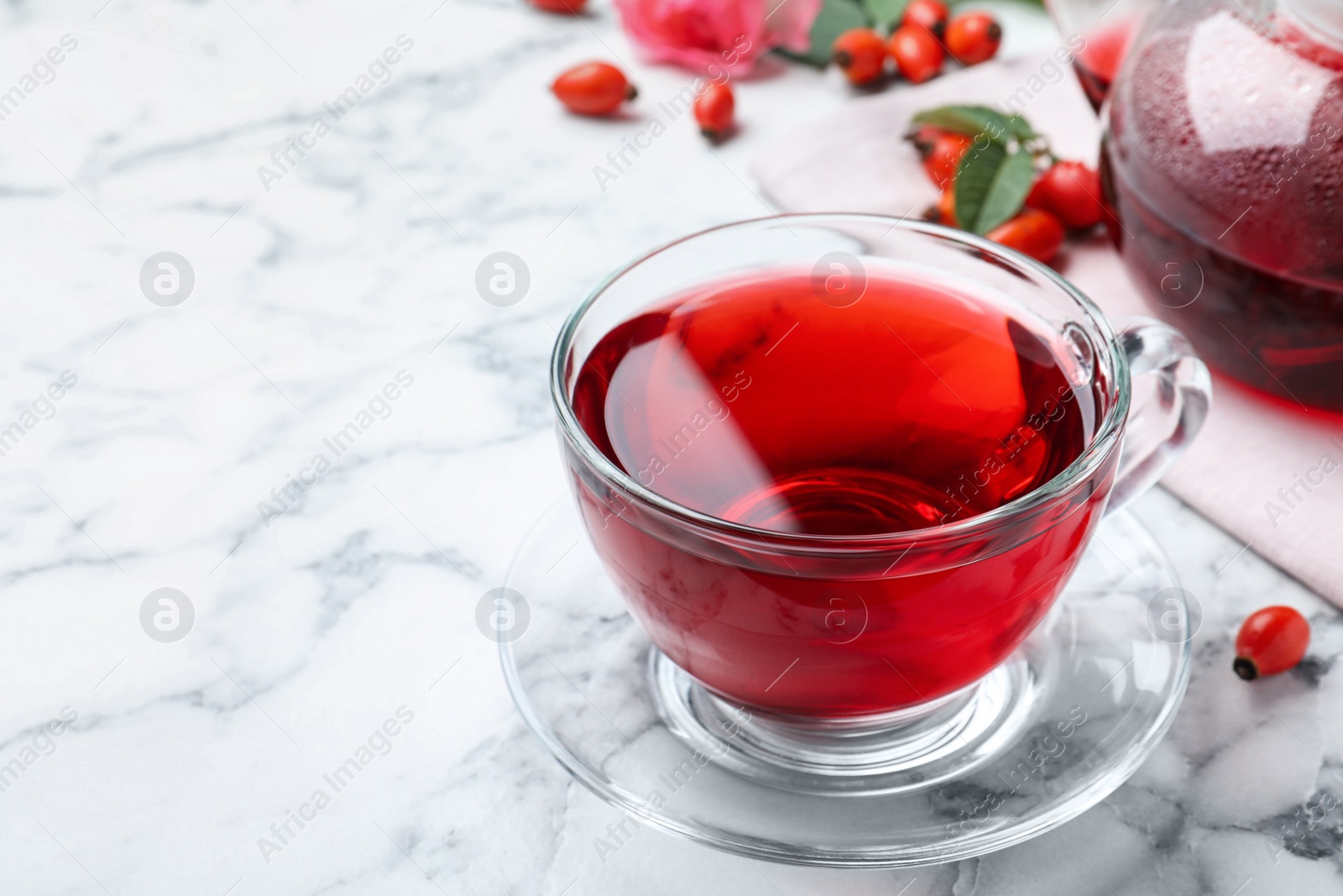 Photo of Fresh rose hip tea and berries on white marble table. Space for text