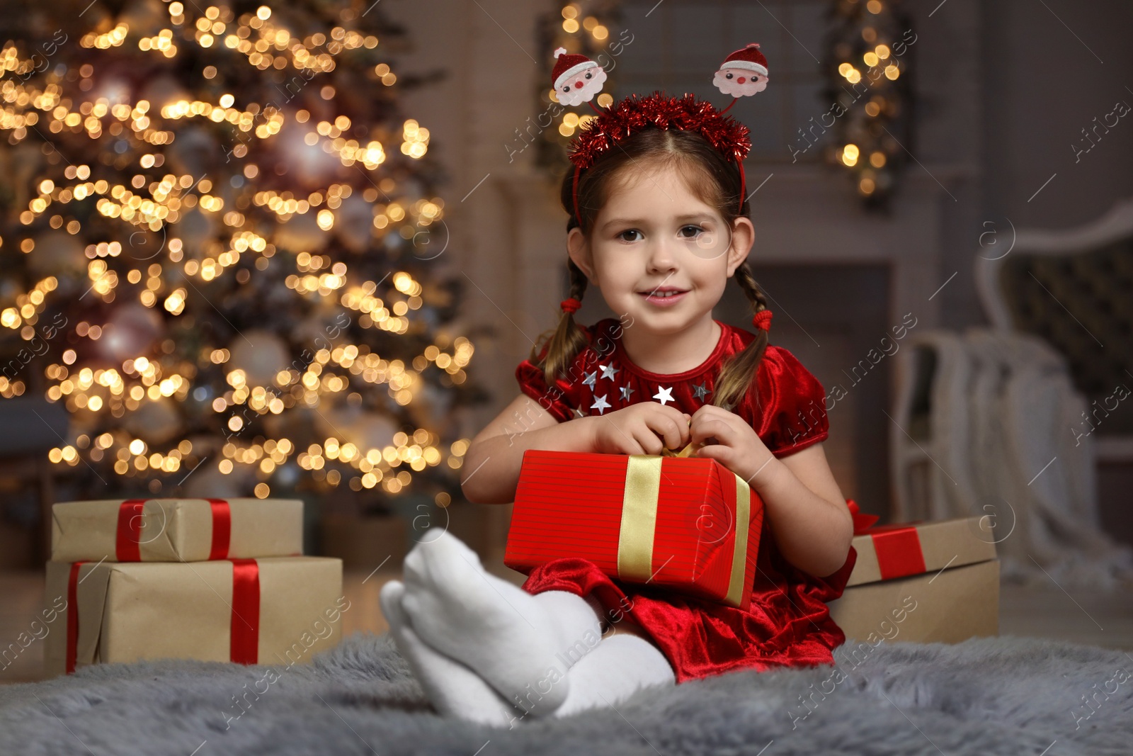 Photo of Cute little child with Christmas gift in living room