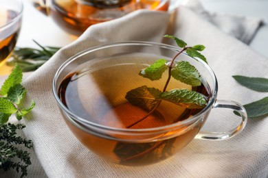 Cup of aromatic herbal tea with mint on table, closeup
