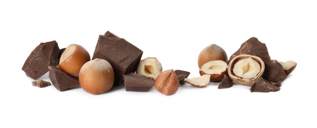 Photo of Delicious chocolate chunks and hazelnuts on white background