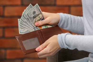 Photo of Woman counting dollar bills near brick wall, closeup. Money exchange