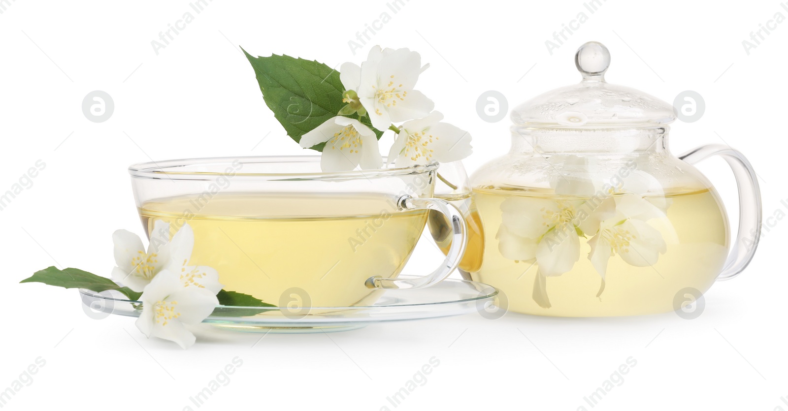 Photo of Aromatic herbal tea in glass cup, teapot and flowers isolated on white