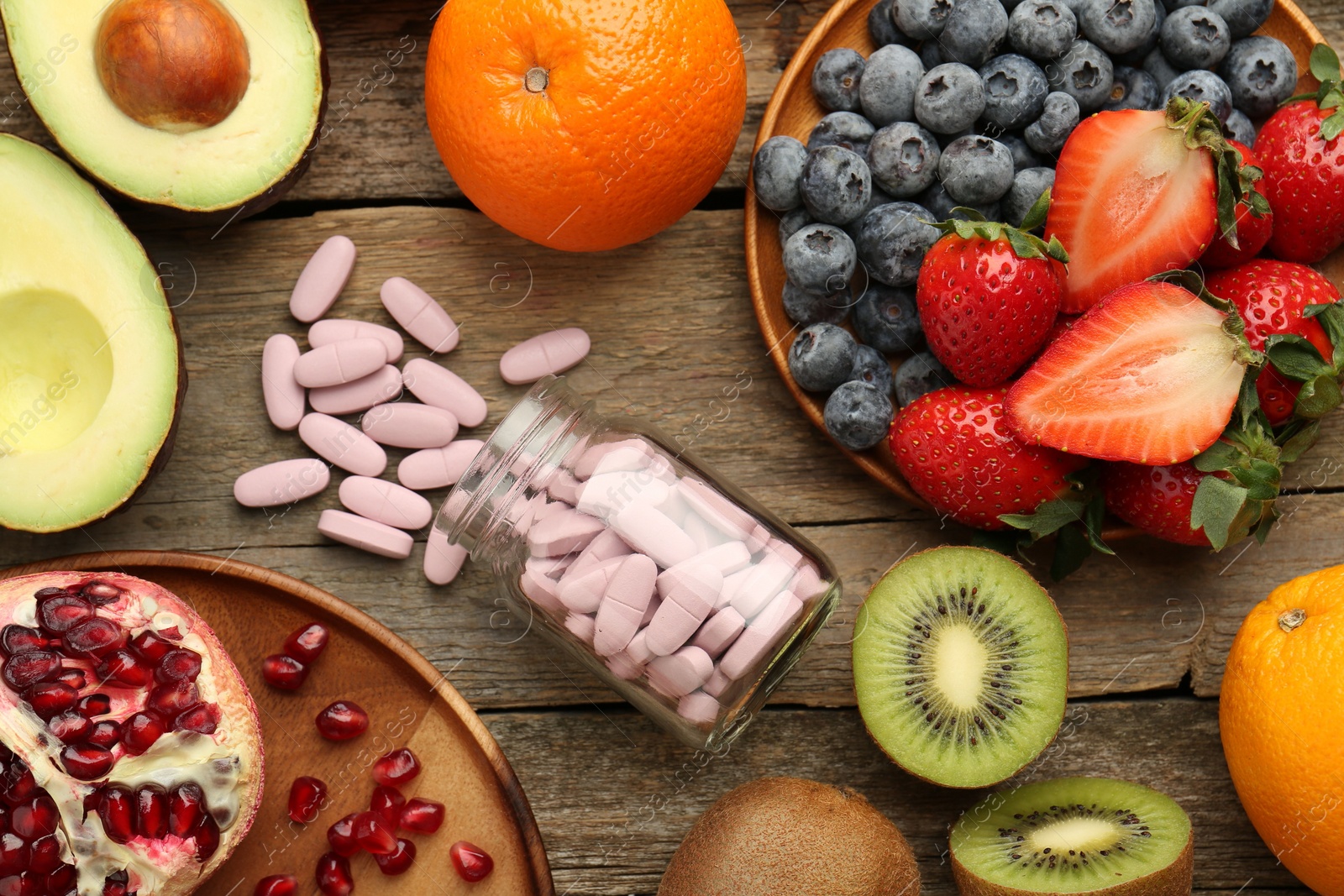 Photo of Vitamin pills in bottle and fresh fruits on wooden table, flat lay