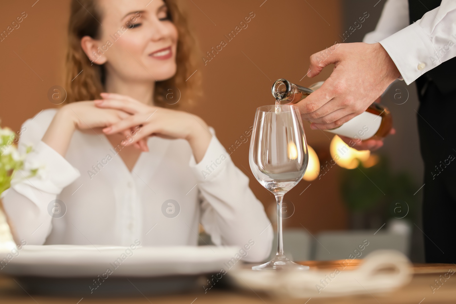 Photo of Waiter pouring wine into glass for client at restaurant