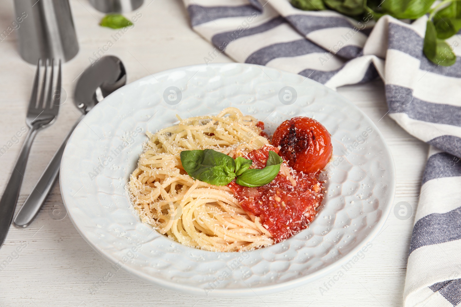 Photo of Tasty pasta with basil and tomato sauce on white wooden table